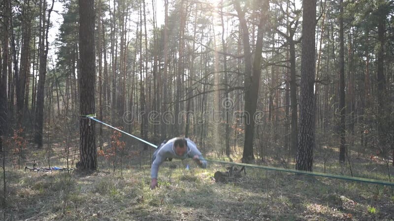 Människan som hoppar och gör trick på slackline i skogen i långsam rörelse lager videofilmer