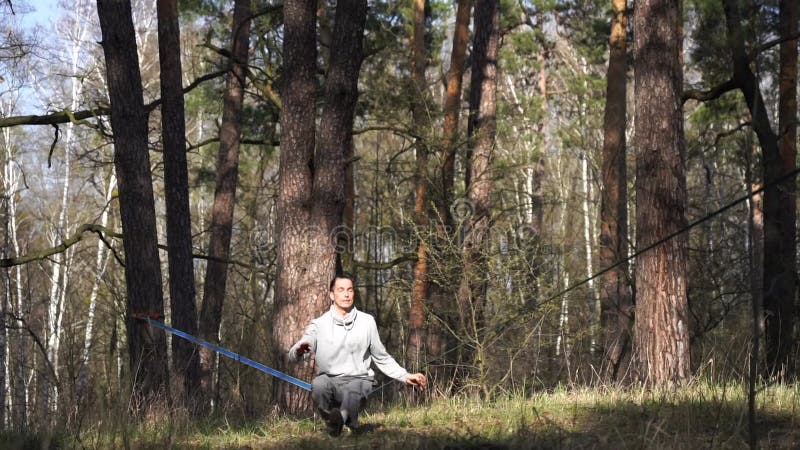 Människan som hoppar och gör trick på slackline i skogen i långsam rörelse lager videofilmer