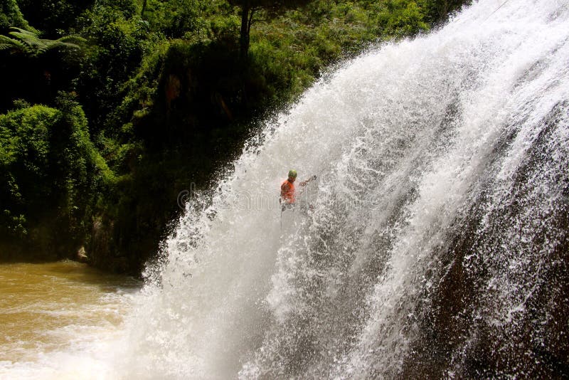 Männliche abseils enormer Wasserfall stockfotos