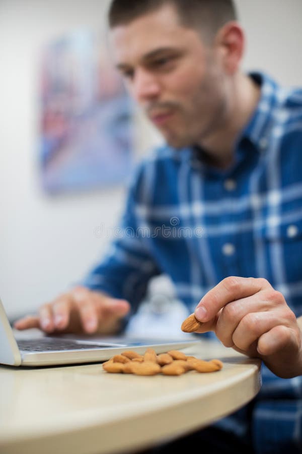 Männliche Arbeitskraft im Büro, das gesunden Snack von Nüssen isst lizenzfreies stockfoto Männliche Arbeitskraft im Büro, das gesunden Snack von Nüssen isst lizenzfreies stockfoto