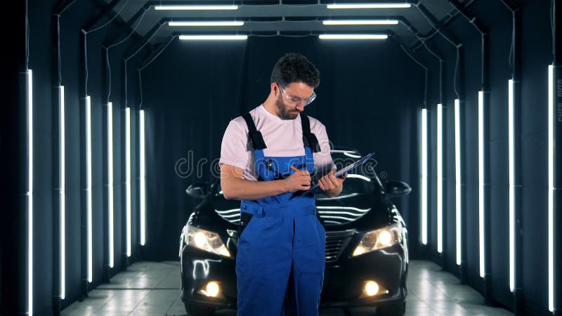 Männliche Arbeitskraft nimmt Kenntnisse und nach der Untersuchung eines Automobils lächelt stock video footage