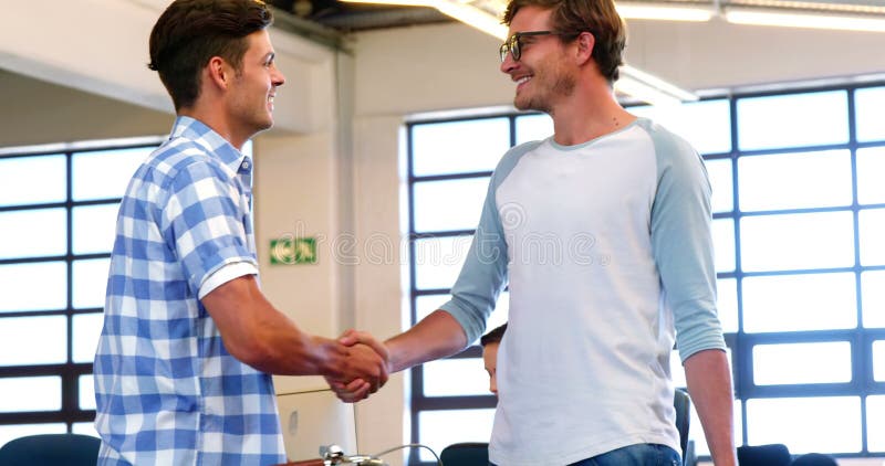 Männliche Führungskräfte, die Hände im Büro rütteln