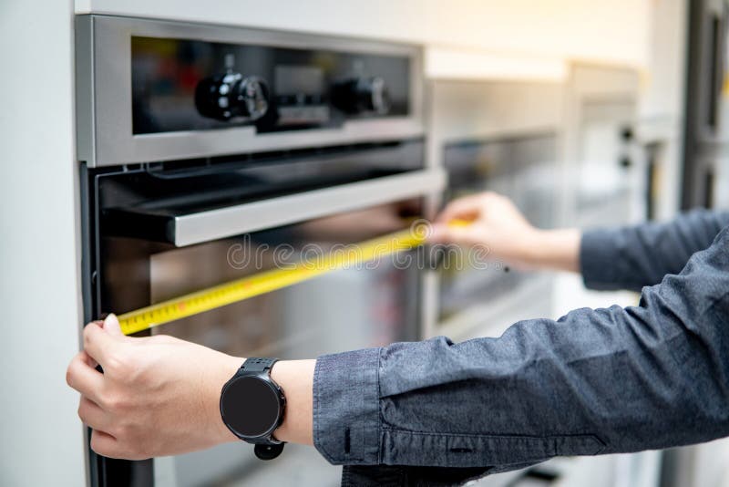 Männliche Hand unter Verwendung des Maßbandes auf Ofen lizenzfreie stockfotos Männliche Hand unter Verwendung des Maßbandes auf Ofen lizenzfreie stockfotos