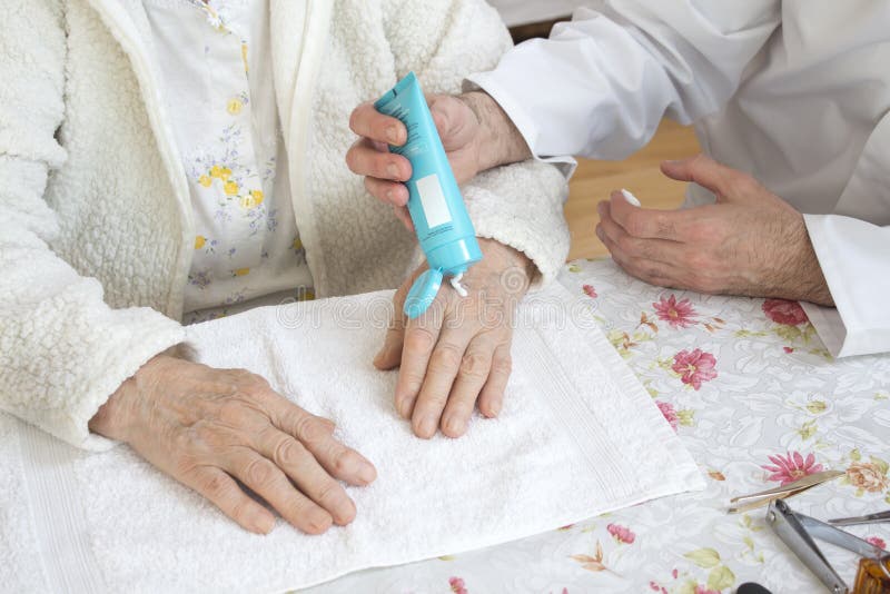 Männliche Krankenschwester setzt die Creme auf die Hand der alten Frau Kosmetische Behandlung und Krankenpflege lizenzfreie stockbilder Männliche Krankenschwester setzt die Creme auf die Hand der alten Frau Kosmetische Behandlung und Krankenpflege lizenzfreie stockbilder