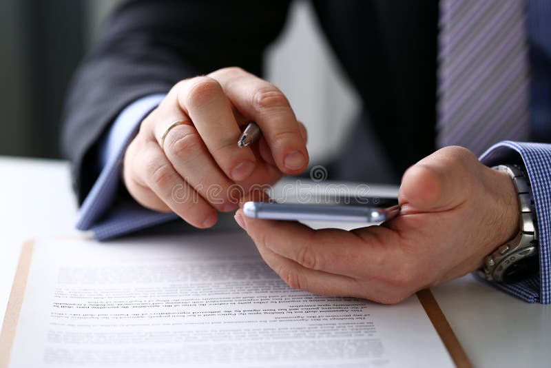 Männlicher Arm im Klagengrifftelefon- und -silberstift an der Arbeitsplatznahaufnahme stockfotos Männlicher Arm im Klagengrifftelefon- und -silberstift an der Arbeitsplatznahaufnahme stockfotos