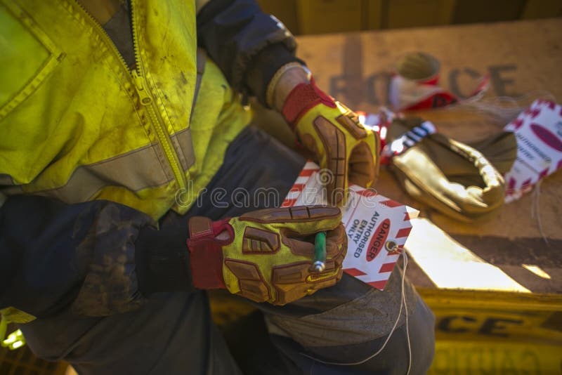Männlicher Industriebauarbeitskraft Rigger, der Detailinformationen über roten und weißen Gefahrenumbau sich krümmt lizenzfreies stockbild Männlicher Industriebauarbeitskraft Rigger, der Detailinformationen über roten und weißen Gefahrenumbau sich krümmt lizenzfreies stockbild