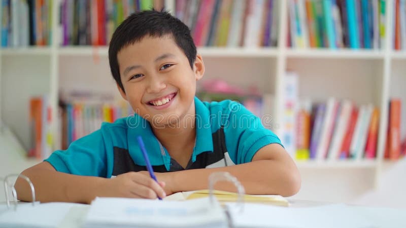 Männlicher jugendlicher Student, der in der Bibliothek lächelt