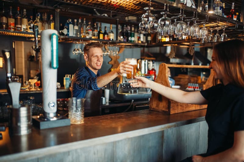Männlicher Kellner führt dem weiblichen Besucher Glas Bier stockbilder Männlicher Kellner führt dem weiblichen Besucher Glas Bier stockbilder