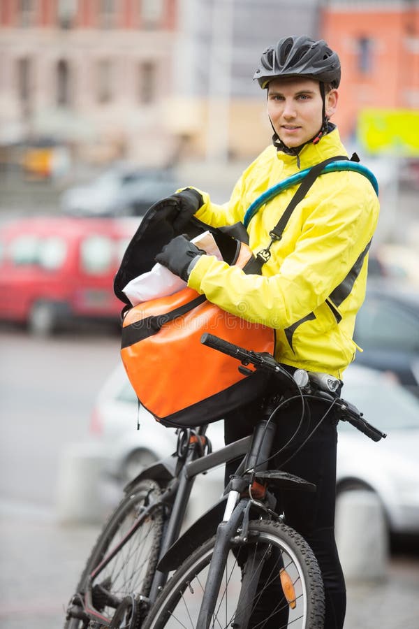Männlicher Radfahrer, der Paket in Kurier Bag On einsetzt lizenzfreie stockfotos Männlicher Radfahrer, der Paket in Kurier Bag On einsetzt lizenzfreie stockfotos