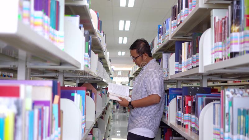 Männlicher Student liest Buch im Bibliotheksgang