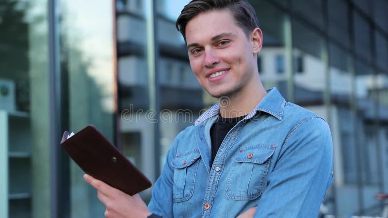 Männlicher Student Reading Notepad Outdoors am College