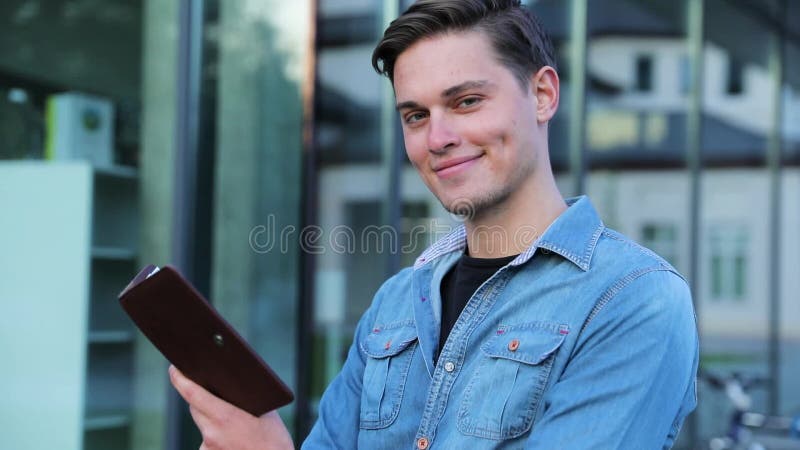 Männlicher Student Reading Notepad Outdoors am College