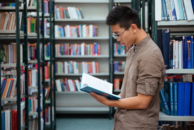 Männlicher Studenten-Reading Book In-Bibliothek stockfotografie Männlicher Studenten-Reading Book In-Bibliothek stockfotografie