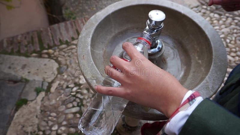 Mänsklig handpåfyllning den återanvända flaskan med vatten från den offentliga typiska vattenspringbrunnen i Granada