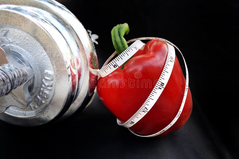 Mäta bandet krulla upp på en röd söt peppar med silverhanteln arkivfoto Mäta bandet krulla upp på en röd söt peppar med silverhanteln arkivfoto