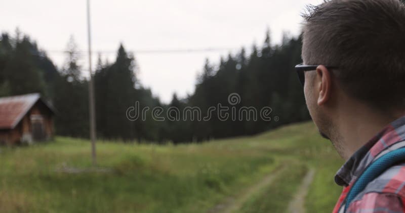 Mężczyzna z brodą w okularach przeciwsłonecznych pokazuje zawieszenie most dla ludzi w górach