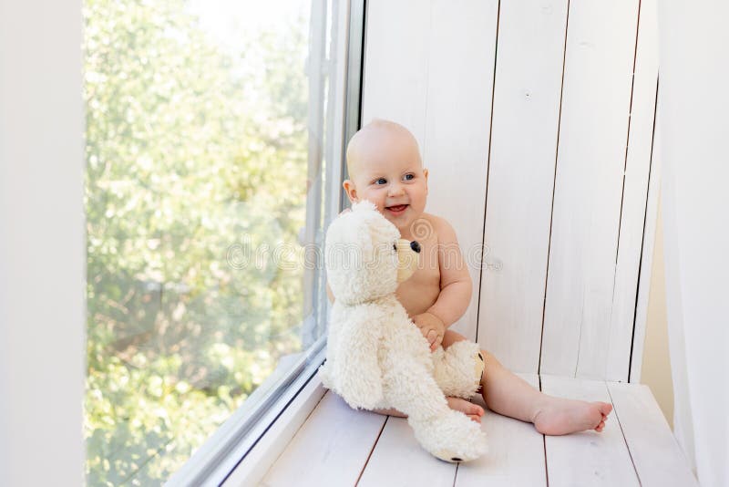 8 månader gammal babypojke som ligger i blöjor på en vit säng med en flaska mjölk i hembenen uppifrån barnmatbegreppet babymat. arkivbild