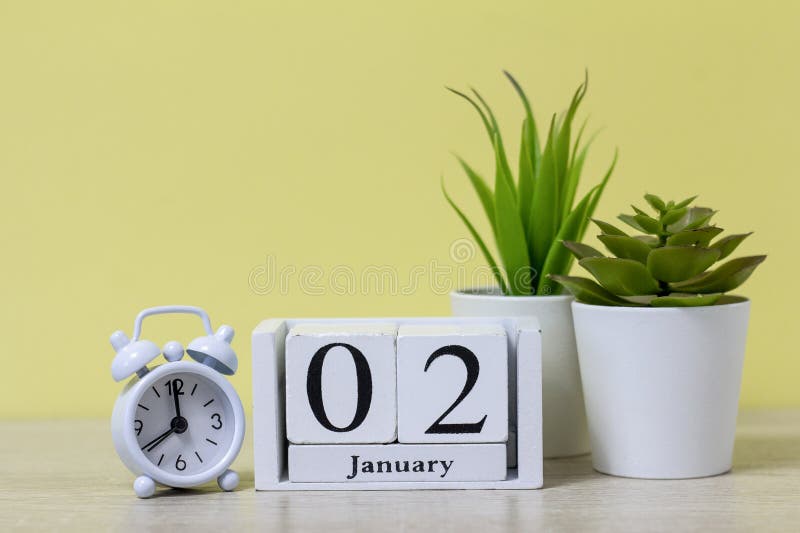 January 2 on a wooden calendar next to the alarm clock is the date of the beginning of the new month and new yea. January 2 on a wooden calendar next to the alarm clock is the date of the beginning of the new month and new yea.