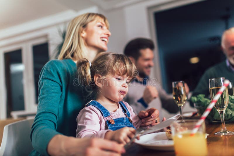 Mång- utvecklingsfamilj som tycker om mål runt om tabellen royaltyfria bilder Mång- utvecklingsfamilj som tycker om mål runt om tabellen royaltyfria bilder