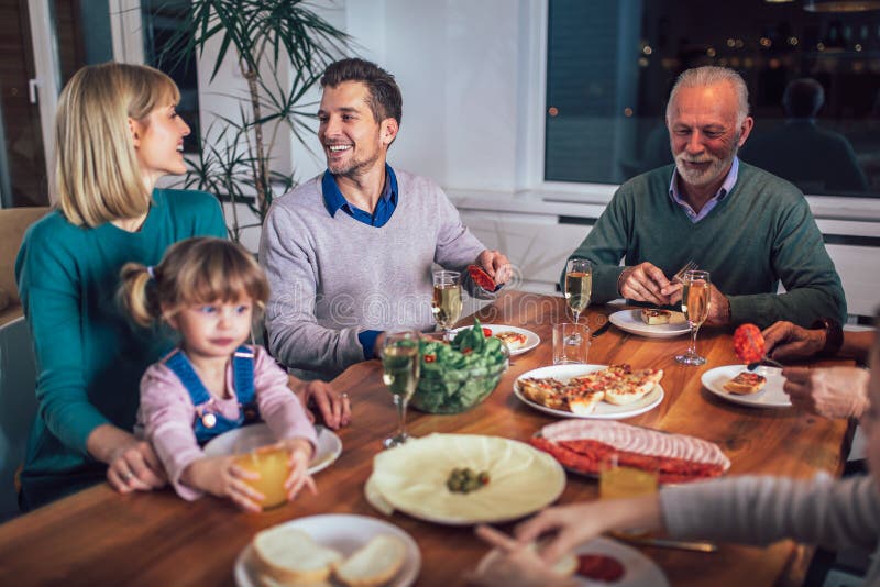 Mång- utvecklingsfamilj som tycker om mål runt om tabellen royaltyfria foton Mång- utvecklingsfamilj som tycker om mål runt om tabellen royaltyfria foton