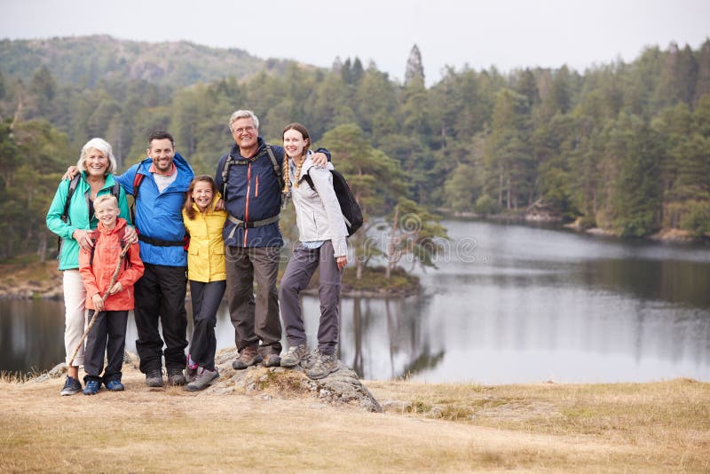 Mång- utvecklingsfamiljställning som omfamnar av en sjö som ler till kameran, främre sikt, sjöområde, UK fotografering för bildbyråer Mång- utvecklingsfamiljställning som omfamnar av en sjö som ler till kameran, främre sikt, sjöområde, UK fotografering för bildbyråer
