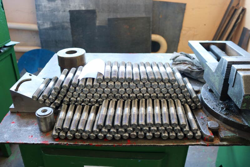 Många skinande metalldubbar med att snida, muttrar, järnringar, packningar, metallarbetehjälpmedel och industriell last på tabell arkivfoton Många skinande metalldubbar med att snida, muttrar, järnringar, packningar, metallarbetehjälpmedel och industriell last på tabell arkivfoton