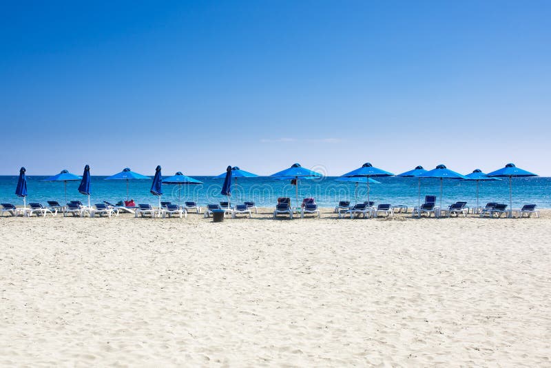 Många strandstolar och paraplyer på det vita sandhavet sätter på land med en blå himmel royaltyfri fotografi Många strandstolar och paraplyer på det vita sandhavet sätter på land med en blå himmel royaltyfri fotografi