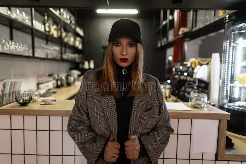 Młoda atrakcyjna elegancka kobieta w modnej nakrętce w retro stylowej w kratkę rocznik kurtce z czerwonymi wargami ostrożnie wpro obraz royalty free