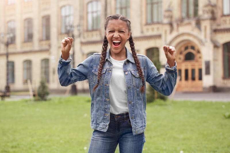 Młoda uczennica stoi przy szkolnym jardem krzyczy denerwujących zamkniętych oczy w cajgach fotografia stock Młoda uczennica stoi przy szkolnym jardem krzyczy denerwujących zamkniętych oczy w cajgach fotografia stock