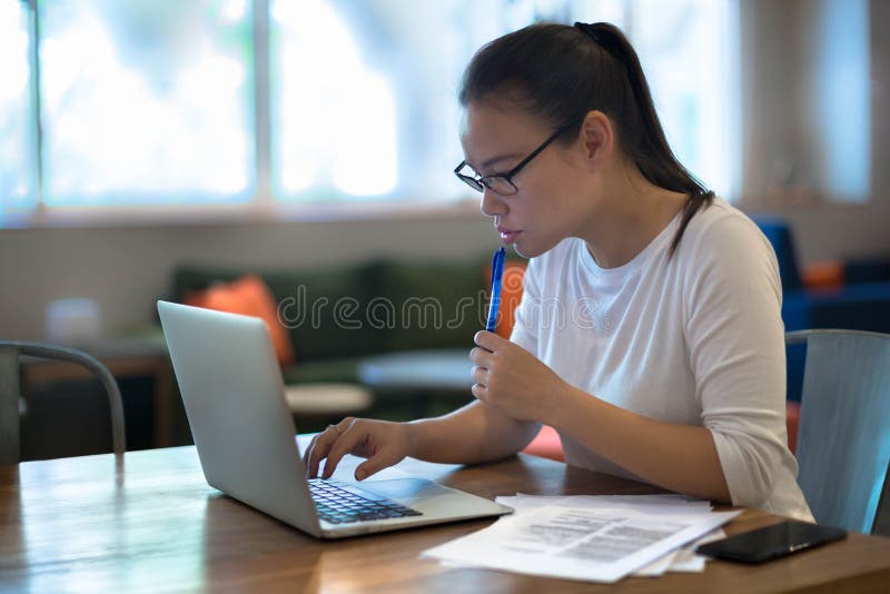 Młode kobiety robi pracie na jej laptopie w domu fotografia stock Młode kobiety robi pracie na jej laptopie w domu fotografia stock