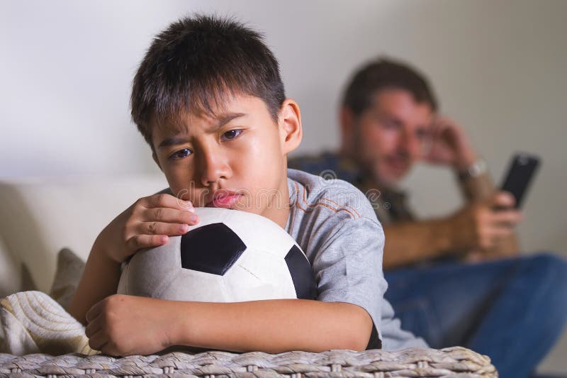 Młody smutnego, zanudzającego dziecko leżanki uczucia czekanie i w domu jego ojciec dla bawić się futbol podczas gdy mężczyzna