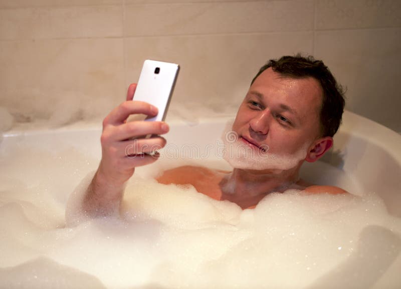 Młody uśmiechnięty mężczyzna siedzi łazienkę robi broda wp8lywy selfie zdjęcia stock Młody uśmiechnięty mężczyzna siedzi łazienkę robi broda wp8lywy selfie zdjęcia stock