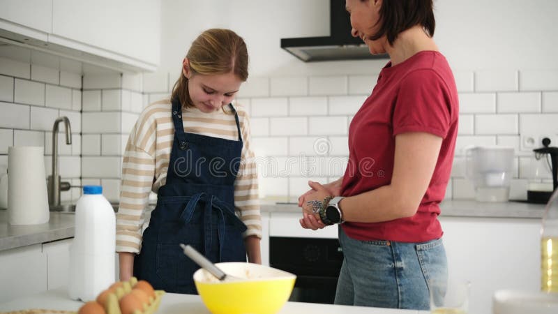 Mère Aide Son Adorable Petite Fille À Mettre Sur Une Cuisine Dans La Cuisine banque de vidéos