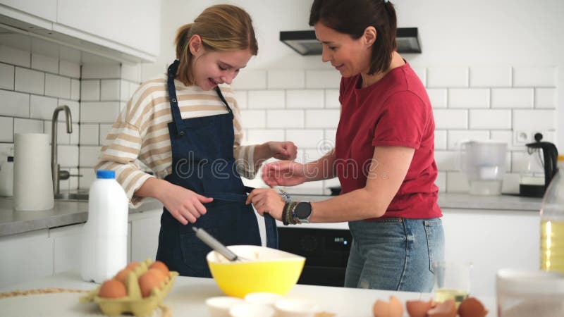 Mère Aide Son Adorable Petite Fille À Mettre Sur Une Cuisine Dans La Cuisine banque de vidéos