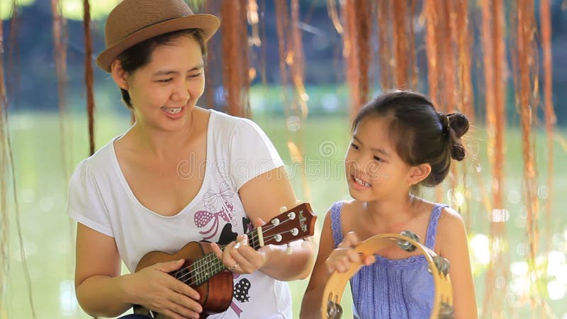Mère asiatique jouant l'ukulélé pour sa fille