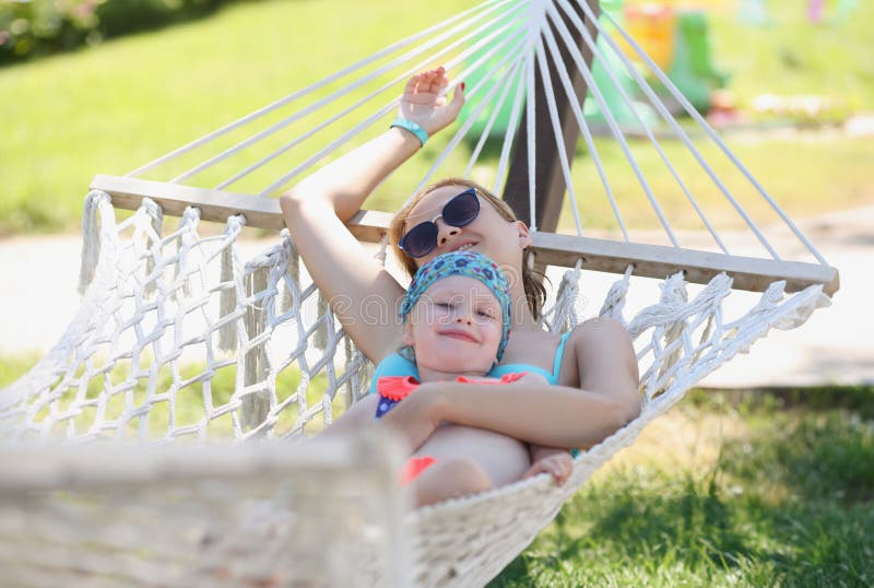 Mère au repos embrasser fille filles allongé hamac dans l'ombre profiter de la vie temps avec la famille photographie stock