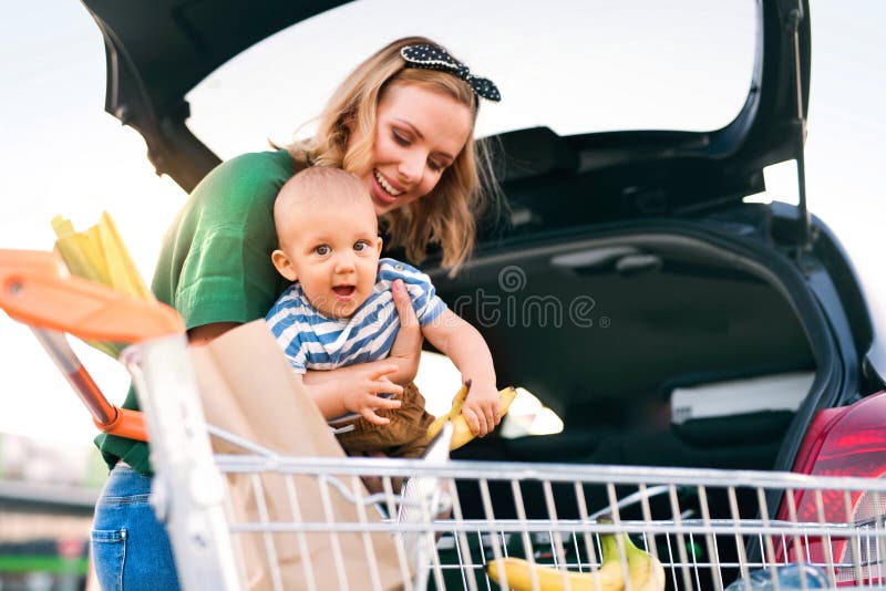 Mère avec le bébé garçon mettant des achats dans le dos de la voiture photo libre de droits Mère avec le bébé garçon mettant des achats dans le dos de la voiture photo libre de droits