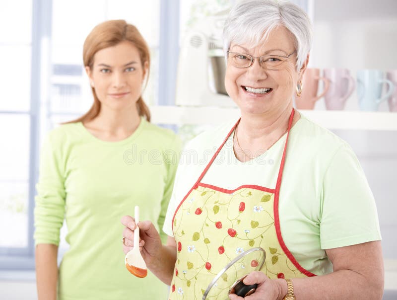 Mère aînée gaie faisant cuire dans la cuisine photo libre de droits