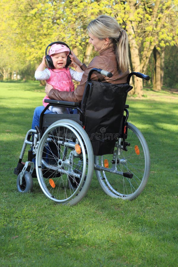 Mère dans un fauteuil roulant avec le bébé sur son recouvrement photo stock Mère dans un fauteuil roulant avec le bébé sur son recouvrement photo stock