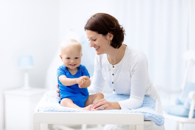 Mère et bébé sur la table changeante photo libre de droits Mère et bébé sur la table changeante photo libre de droits