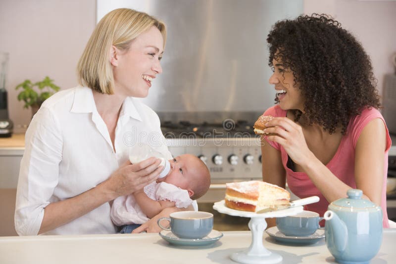 Mother and baby in kitchen with friend eating cake. Mother and baby in kitchen with friend eating cake