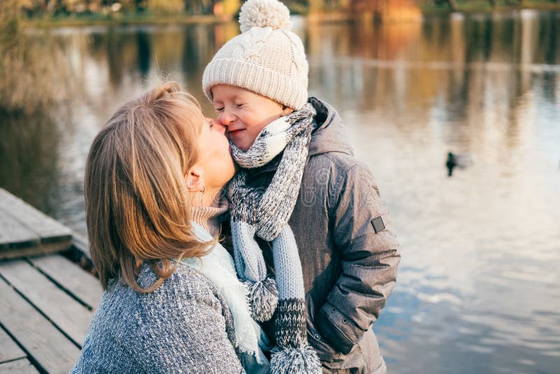 Mère et enfant étreignant au parc d'automne près du lac Fils heureux avec la maman ayant l'amusement, détente, appréciant la vie image stock Mère et enfant étreignant au parc d'automne près du lac Fils heureux avec la maman ayant l'amusement, détente, appréciant la vie image stock