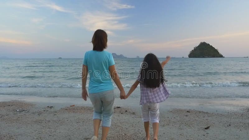 Mère et fille asiatiques heureuses des vacances à la plage, mouvement lent