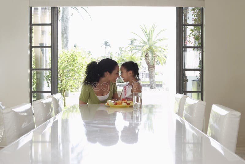 Mère et fille espiègles à la table de salle à manger photographie stock