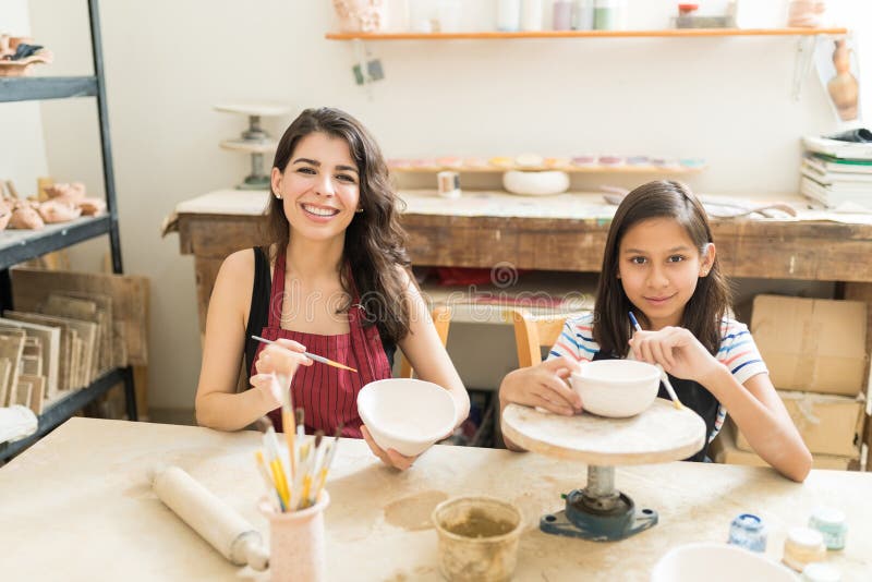 Mère et fille montrant leur poterie innovatrice peignant Te image stock Mère et fille montrant leur poterie innovatrice peignant Te image stock