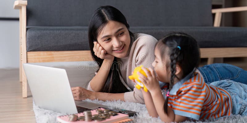 Mère et fille profitant d'une session amusante d'apprentissage sur l'économie d'argent avec un ordinateur portable et une tirelire images libres de droits