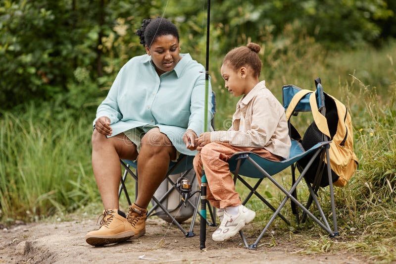 Mère et fille pêchent ensemble en plein air pendant qu'ils campent image stock