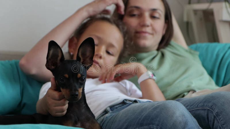 Mère et fille s'amuser avec le chien dans le canapé.