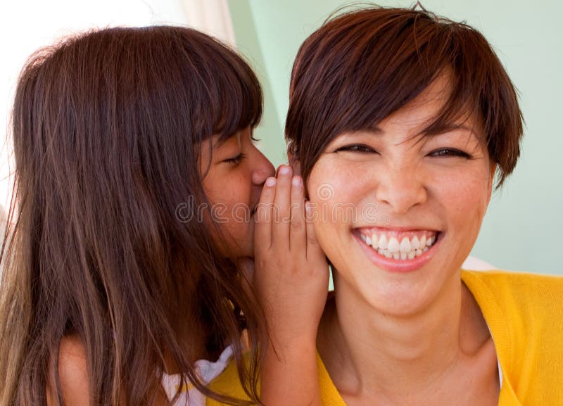 Mère et fille souriant et disant des secrets photographie stock libre de droits Mère et fille souriant et disant des secrets photographie stock libre de droits