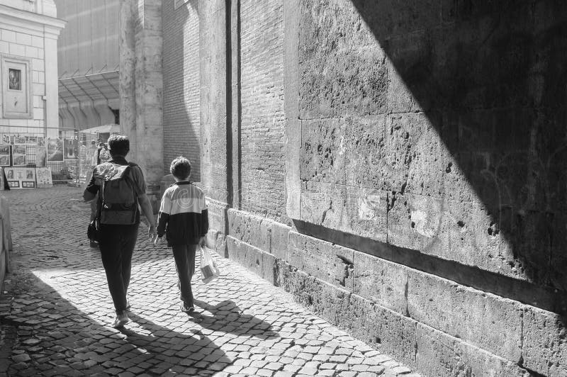 A mother and her young boy walking through an alleyway on cobble-stoned street in Rome, Italy. A mother and her young boy walking through an alleyway on cobble-stoned street in Rome, Italy